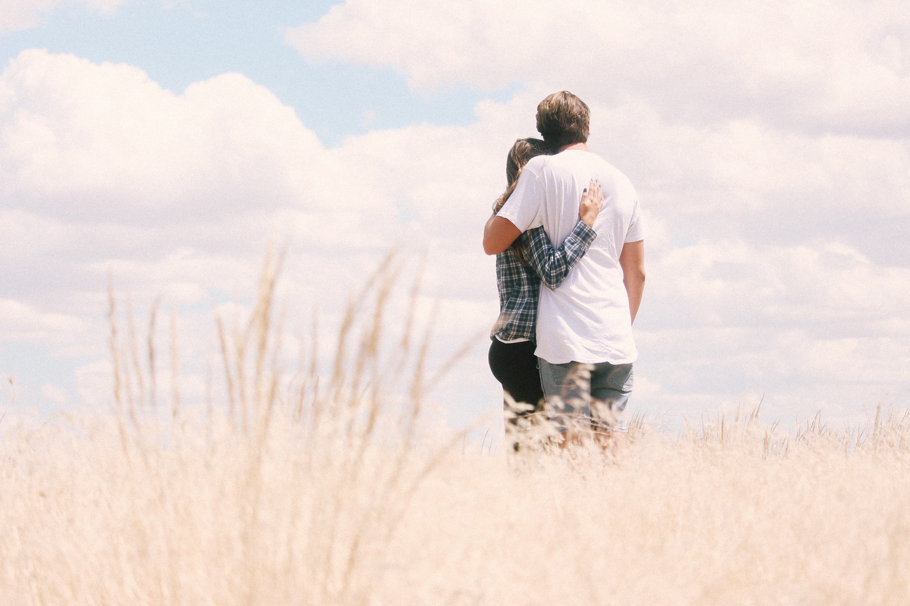 A couple hugging in a field of wild grass