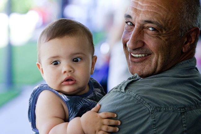 Granddad holding grandchild and smiling