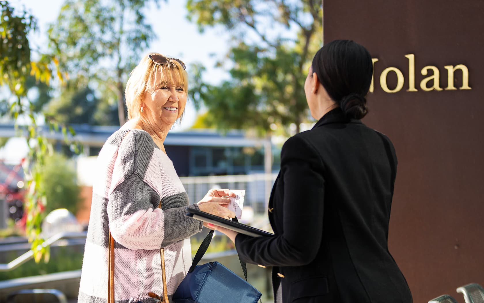 Event staff assisting a customer by providing directions at a Mother's Day remembrance event, creating a welcoming and organised atmosphere.