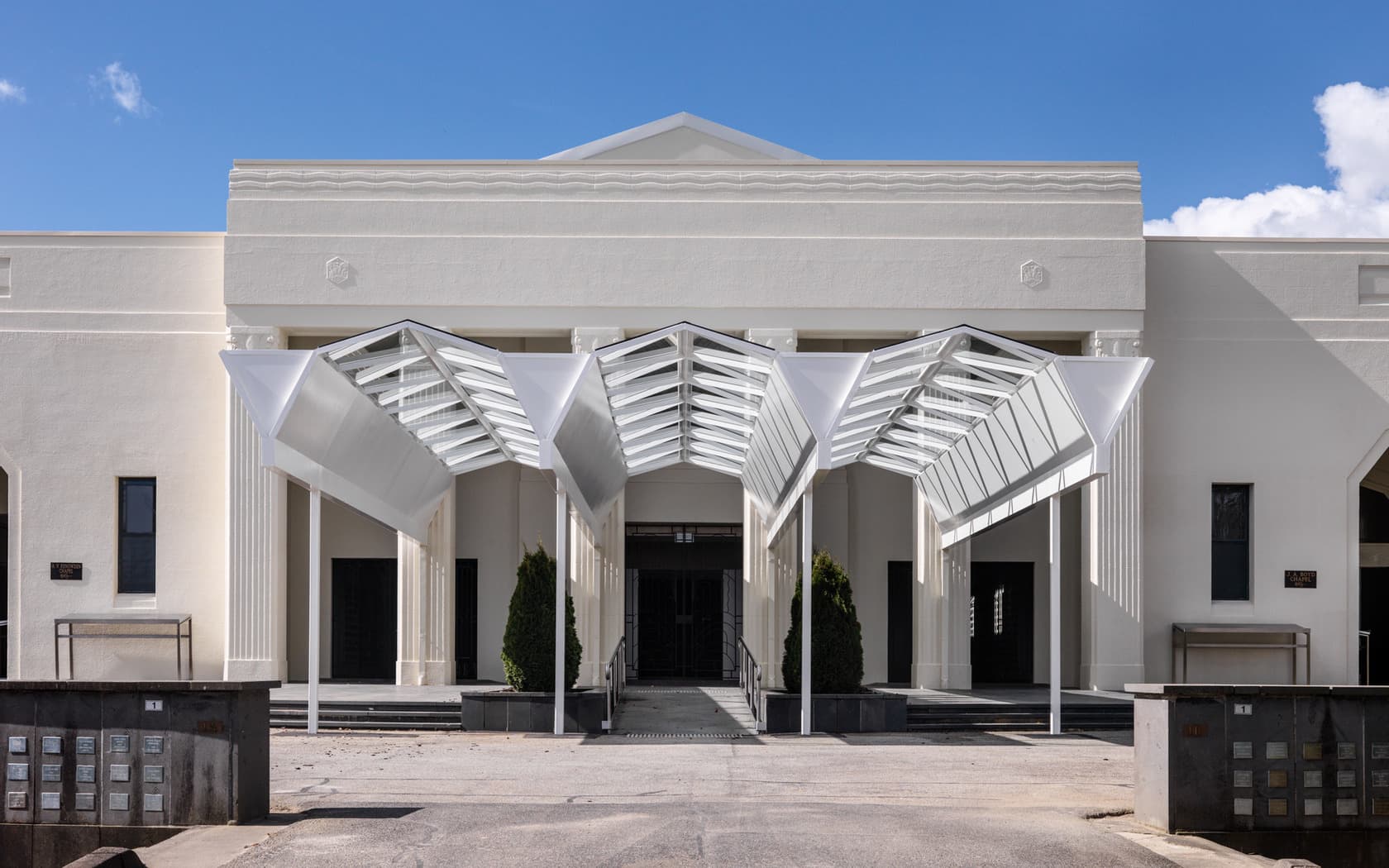 Large white cemetery chapel building under a clear sky, symbolising peace and remembrance